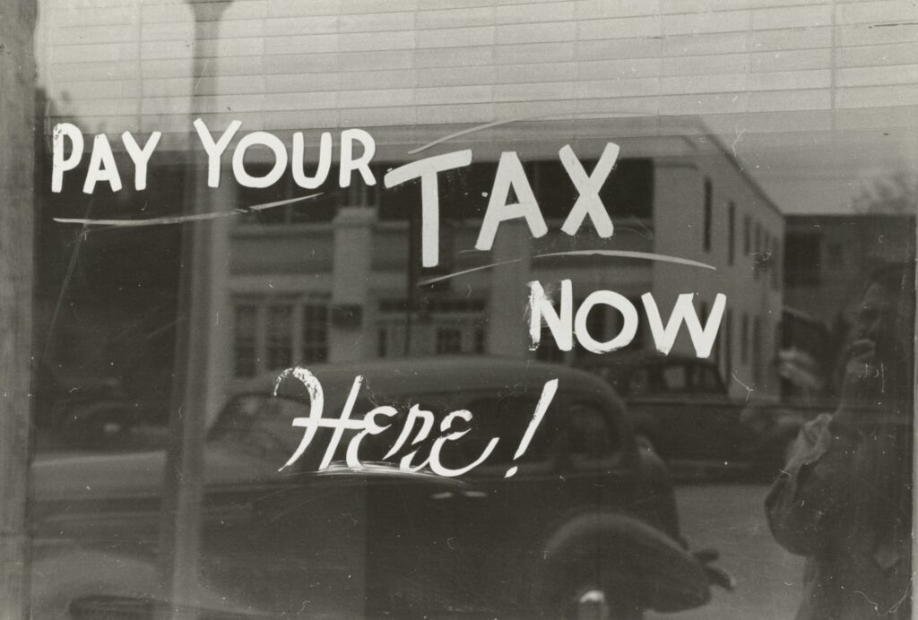A sign that says Pay Your Tax Now Here!