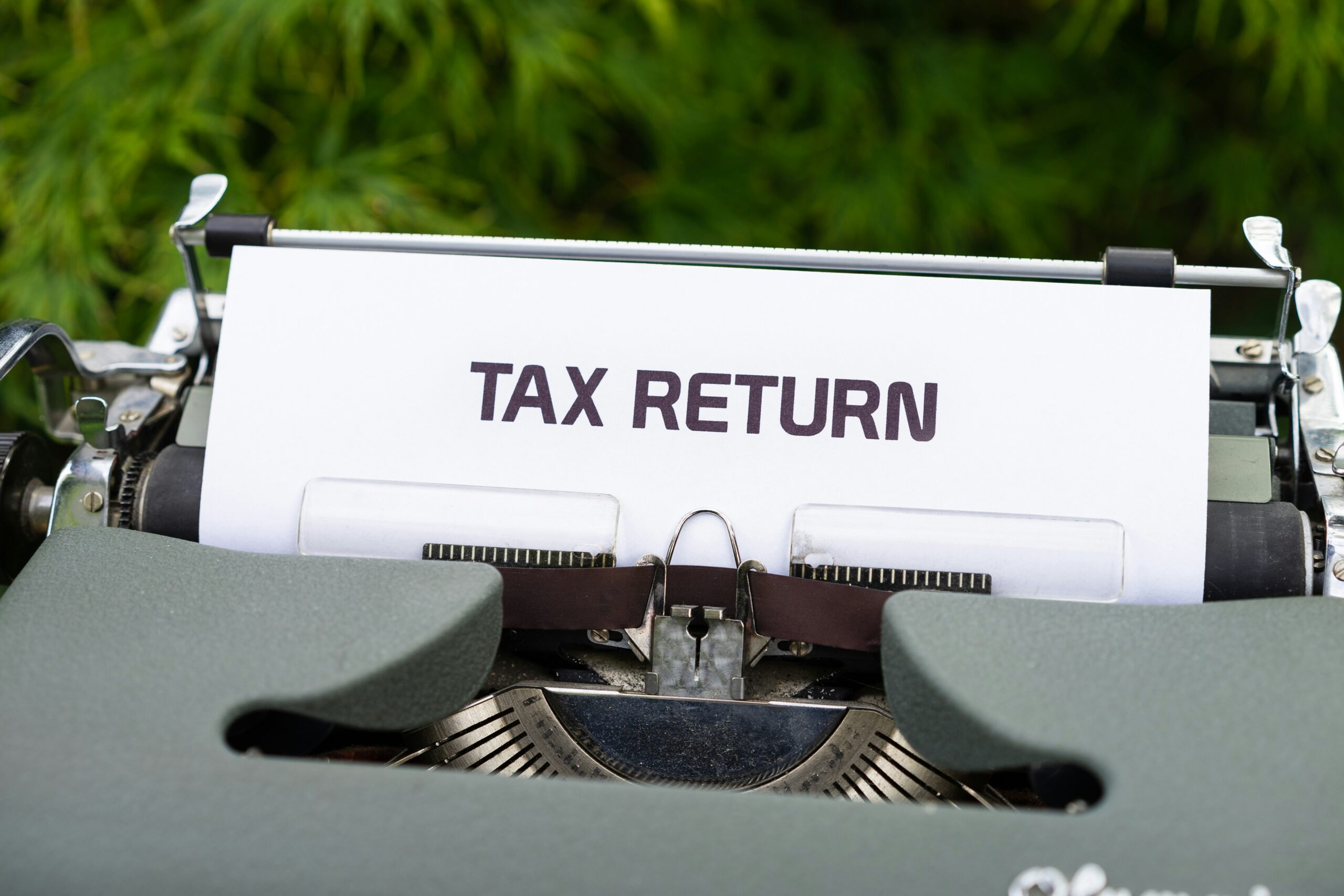 A close up of a typewriter with a tax return sign on it.